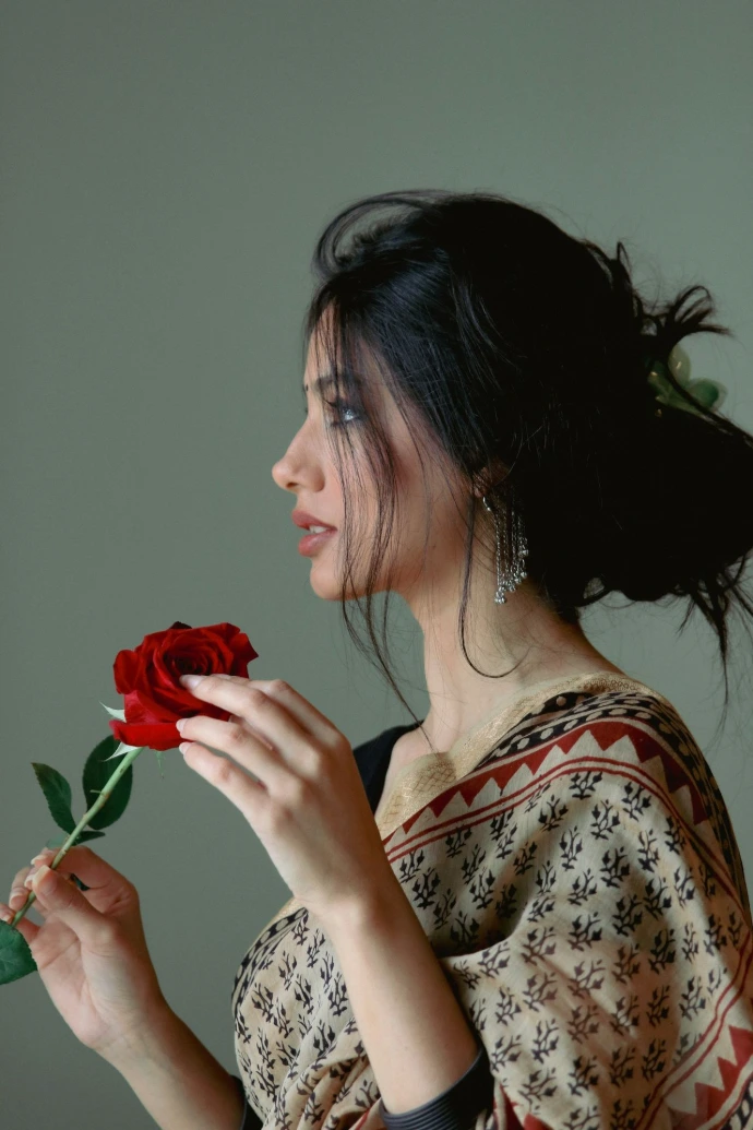 A woman is holding a rose in her hand